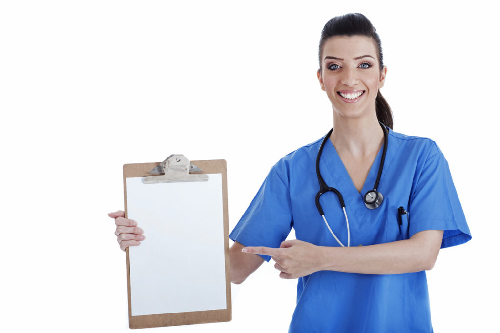 Portrait of young nurse pointing blank clipboard over isolated white background